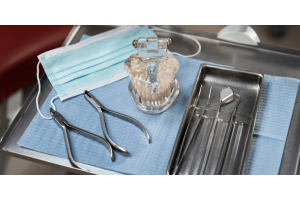 Dental tools, including pliers and mirrors, arranged on a tray in a dental chair.