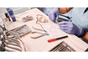 A person seated in a dental chair, focused on a dental instrument, preparing for a procedure.