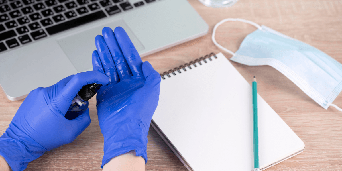  A person wearing blue gloves is typing on a laptop, focused on their work.
