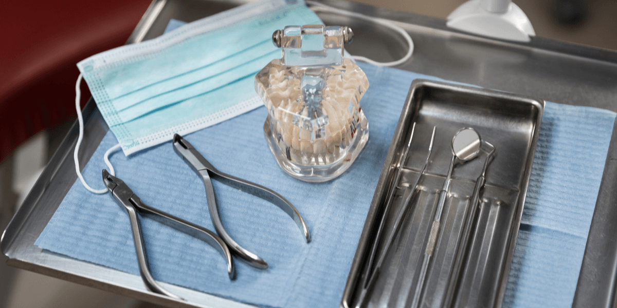 Dental tools, including pliers and mirrors, arranged on a tray in a dental chair.