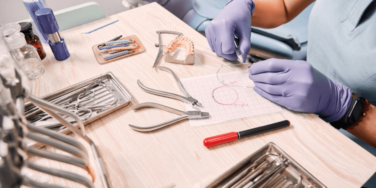 A person seated in a dental chair, focused on a dental instrument, preparing for a procedure.