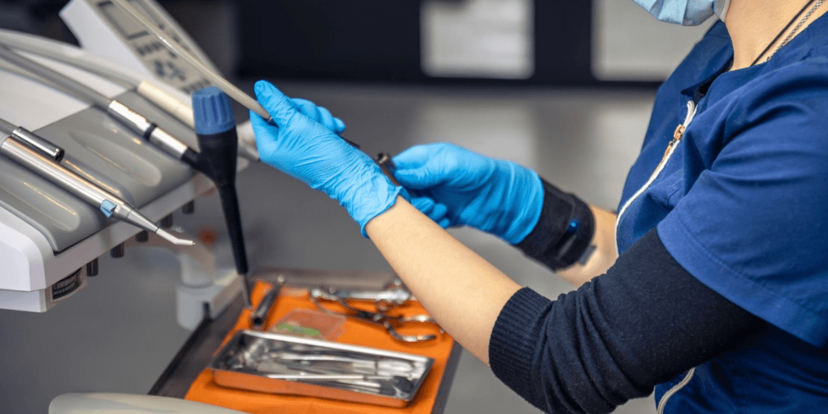 A woman wearing blue gloves is using a dental tool, focused on a dental procedure.